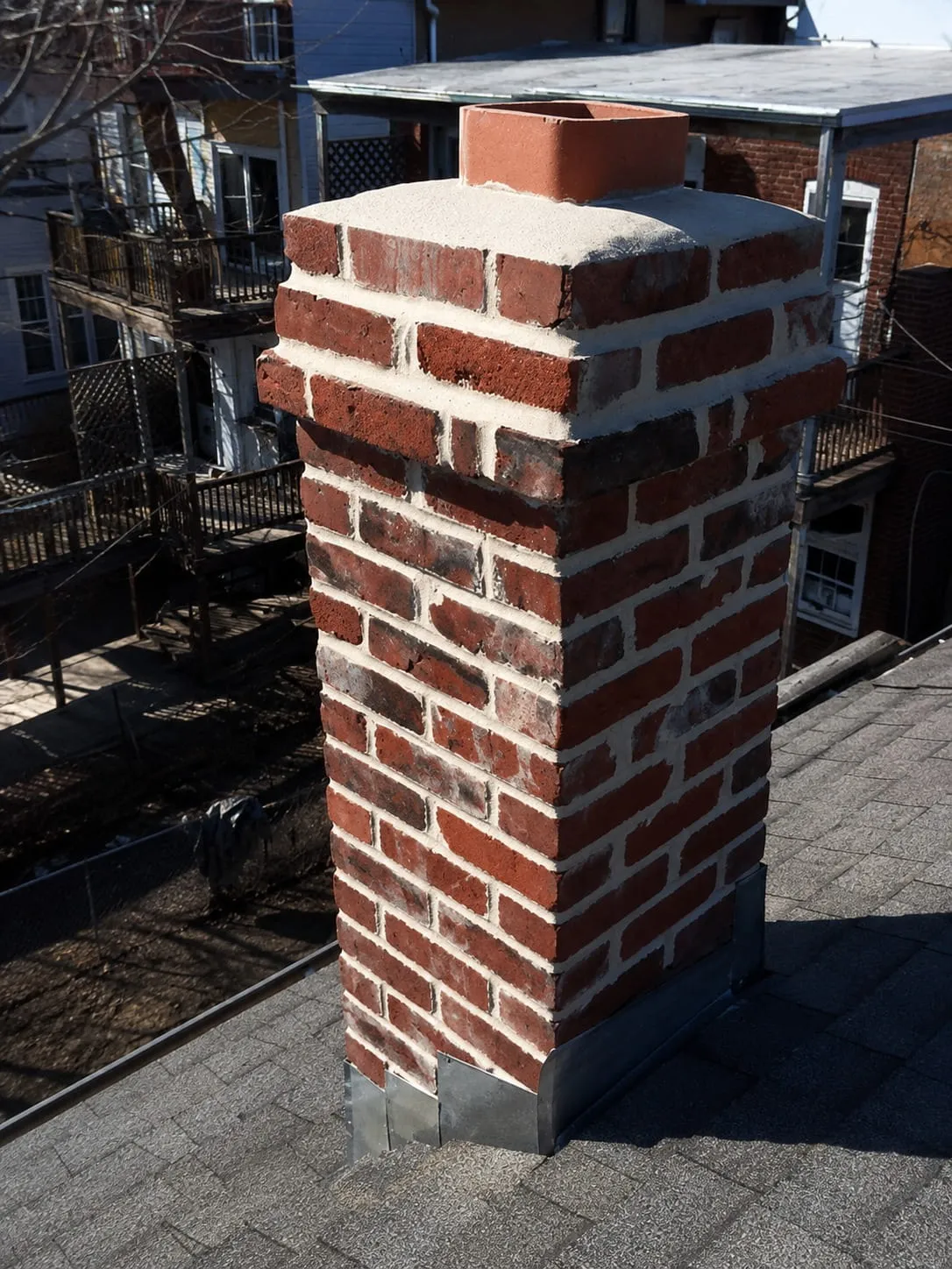 Repointed brick chimney with a new crown and flashing above a Washington DC rooftop