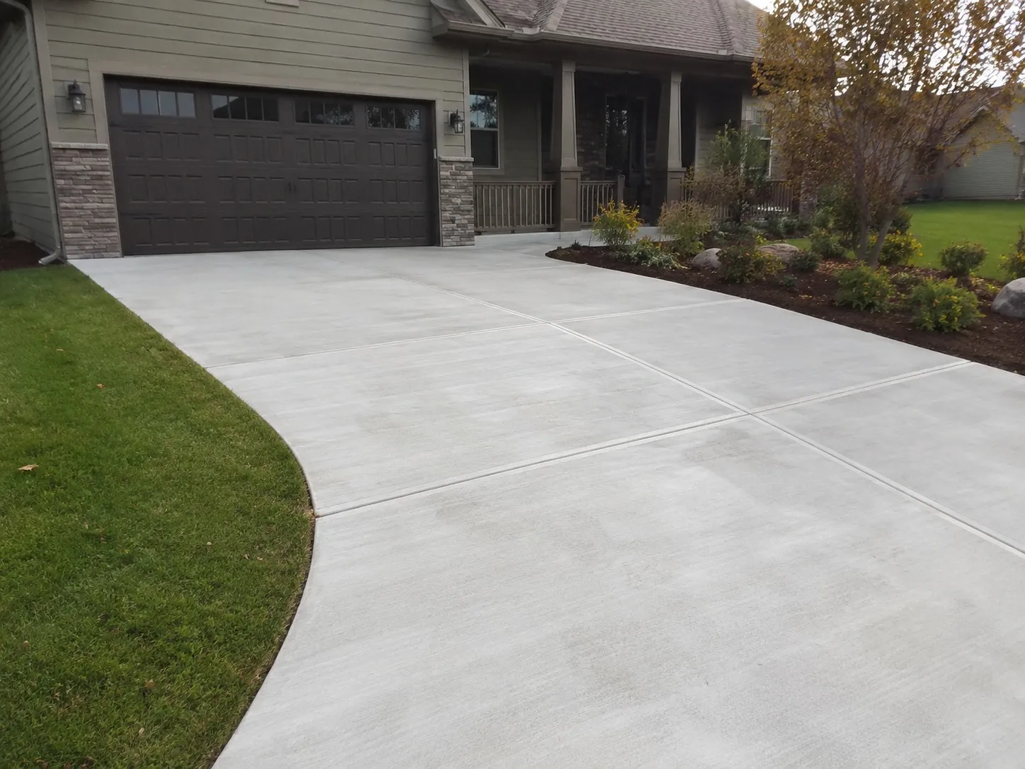 Smooth poured concrete slab with jointed sections curving up to a garage