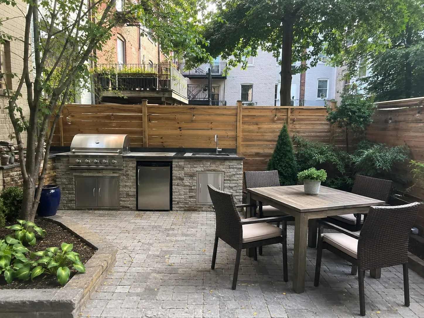 Custom paver patio with a built-in stone outdoor kitchen and dining area in a Washington DC courtyard