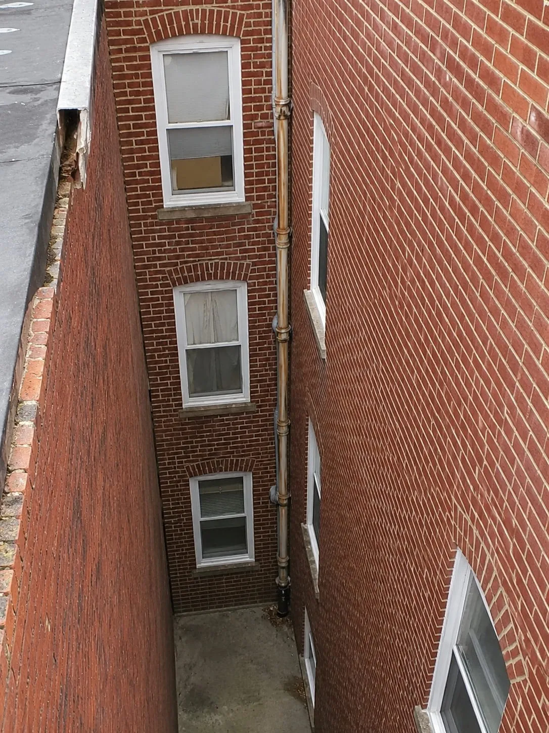 Restored brickwork and repointed mortar joints along a narrow rowhouse light well