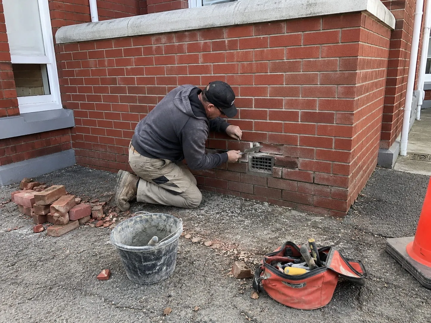 Mason cutting out and replacing damaged brick at the base of a Washington DC wall