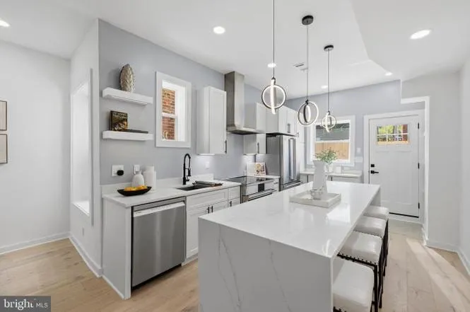 Open-plan kitchen with a quartz waterfall island and pendant lighting in a renovated DC rowhouse