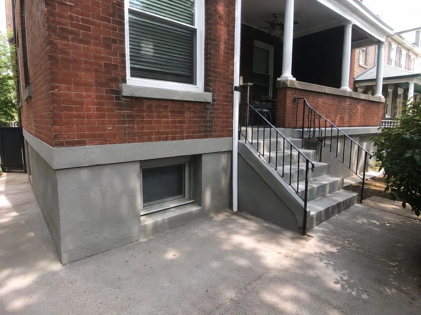 Finished smooth grey parging along the foundation of a red brick Washington DC rowhouse