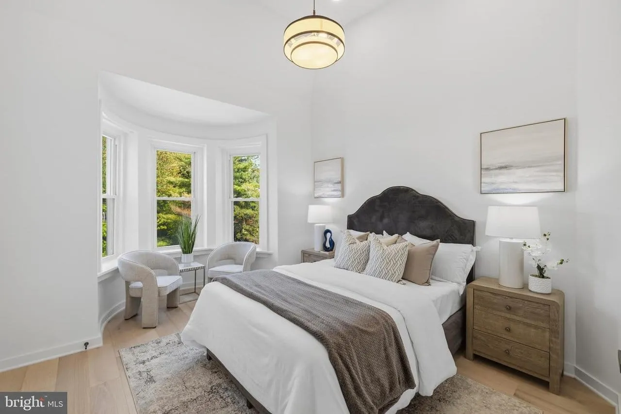 Restored primary bedroom with an original curved bay window and white oak floors