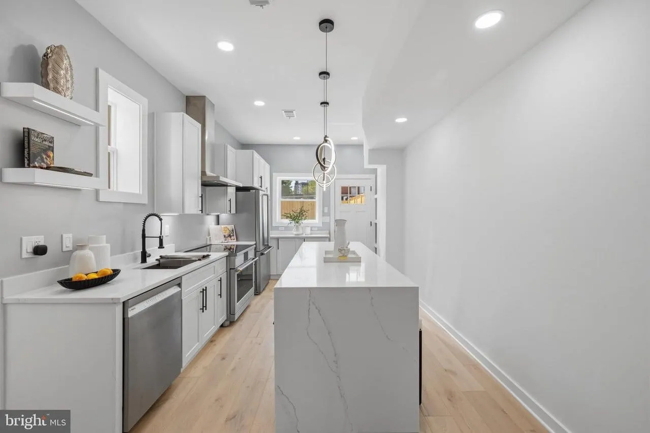 Renovated galley kitchen with a quartz waterfall island and white oak floors in a Washington DC rowhouse