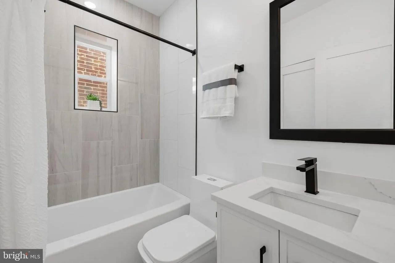 Finished bathroom in a converted Washington DC condo unit, with a tiled shower and quartz vanity