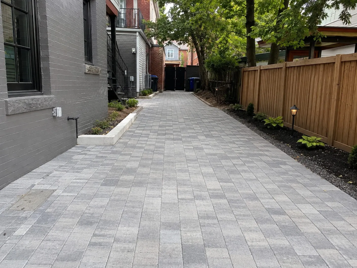Long paver walkway running between a Washington DC rowhouse and a fenced garden border