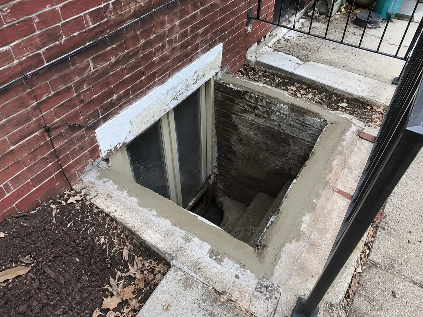 Rebuilt areaway and window well with fresh parged walls outside a Washington DC rowhouse basement window